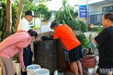 Cán bộ ngành Y tế Đắk Lắk hướng dẫn người dân thị xã Buôn Hồ diệt lăng quăng, bọ gậy phòng chống bệnh viêm não Nhật Bản. (Ảnh: Quang Nhật).