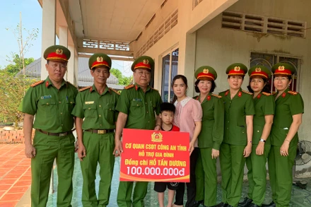 Lãnh đạo, chỉ huy khối điều tra trao tượng trưng số tiền 100 triệu đồng cho cháu Hồ Gia Bảo. (Ảnh: ĐOÀN DIỂU)
