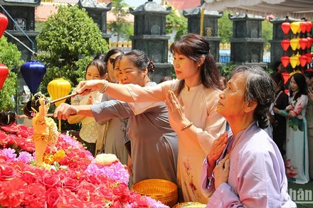 Chư tăng, phật tử cùng bà con kiều bào thực hiện nghi lễ tắm Phật. (Ảnh: Hải Tiến)