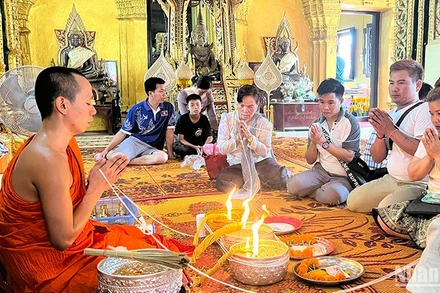 Người dân Lào tham gia nghi lễ buộc chỉ cổ tay đón năm mới 2567 theo Phật lịch của Lào. Ảnh: Trịnh Dũng