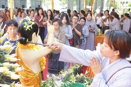 Chư Tăng, Phật tử và bà con kiều bào thực hiện các nghi lễ Tắc Bạt và tắm Phật. (Ảnh: HẢI TIẾN)