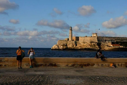Du khách đeo khẩu trang sau khi chụp ảnh tại đại lộ El Malecon ven biển, ngày 7/2/2022. (Ảnh: Reuters)