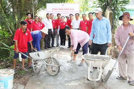 Thành viên Hội Chữ thập đỏ xã Đông Thạnh, thị xã Bình Minh (tỉnh Vĩnh Long) tham gia vá đường giao thông nông thôn. (Ảnh: BÁ DŨNG)