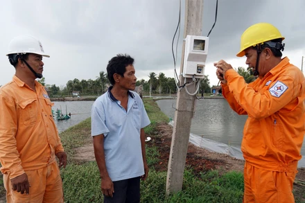 Công nhân Điện lực huyện Mỹ Xuyên, tỉnh Sóc Trăng hướng dẫn, tuyên truyền cho các hộ gia đình sử dụng điện an toàn trong nuôi tôm. (Ảnh: THẾ VĨNH)
