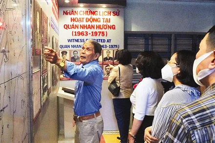 Du khách nghe giới thiệu về hoạt động của lực lượng biệt động Sài Gòn tại Nhan Hương quán, một điểm đến trong tour “Theo dấu chân biệt động Sài Gòn”. (Ảnh: HOÀNG TUYẾT)