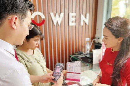 Nhân viên ngân hàng hướng dẫn khách hàng thanh toán không dùng tiền mặt. (Ảnh: CTV)