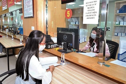 Cán bộ tại bộ phận một cửa của Sở Kế hoạch và Đầu tư Hà Nội hướng dẫn, hỗ trợ doanh nghiệp thực hiện thủ tục hành chính. (Ảnh: MINH HÀ)