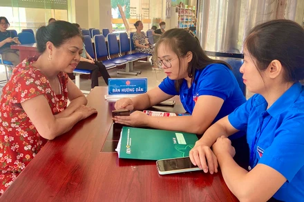 Ðoàn viên, thanh niên tỉnh Bắc Kạn hướng dẫn người dân sử dụng các dịch vụ công qua điện thoại di động. (Ảnh THU TRANG)