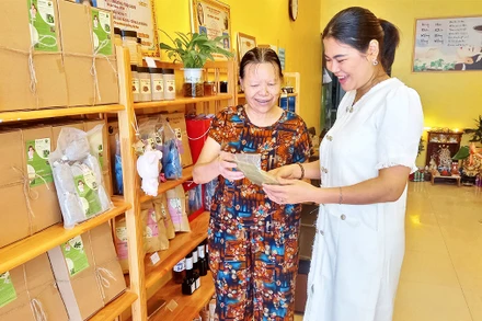 Chị Ðinh Thị Minh Thanh (phải) giới thiệu sản phẩm thảo dược chăm sóc sức khỏe với khách hàng.