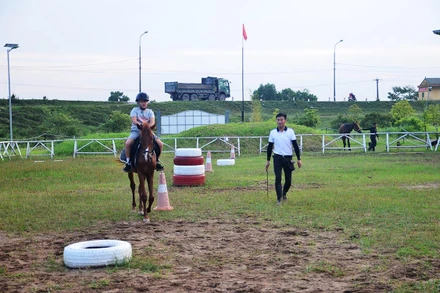 Ðoàn Văn Hưởng hướng dẫn một bé trai cưỡi ngựa.