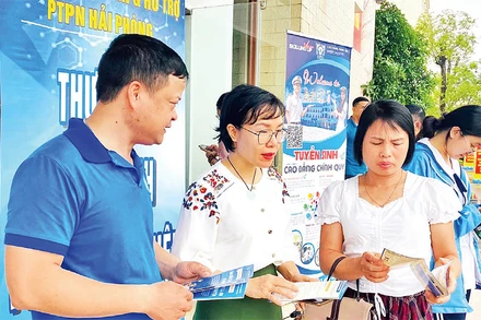 Cán bộ Bảo hiểm xã hội Hải Phòng tuyên truyền chính sách bảo hiểm xã hội tự nguyện, bảo hiểm y tế hộ gia đình tại các phiên giao dịch việc làm. (Ảnh QUANG MINH)