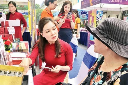 Cán bộ ngân hàng hướng dẫn người dân cách thanh toán không dùng tiền mặt.