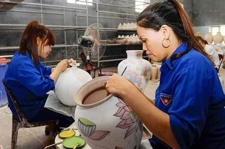 Vẽ hoa văn lên sản phẩm tại làng gốm Bát Tràng, Hà Nội. (Ảnh TUỆ NGHI)