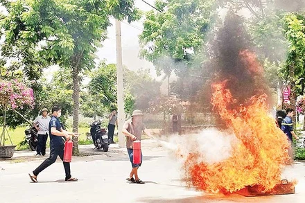 Người dân xã Yên Mỹ, huyện Thanh Trì thực hành sử dụng bình chữa cháy để dập lửa. (Ảnh NGUYỄN QUÂN)