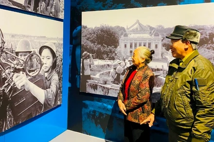 Bà Đặng Thị Ty cùng chồng ngắm bức ảnh của chính mình khi đang chiến đấu năm xưa. (Ảnh NVCC)