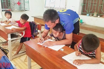 Thầy giáo dạy học sinh đồng bào Mã Liềng ở huyện Tuyên Hóa (Quảng Bình) viết chữ.