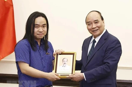 Chủ tịch nước Nguyễn Xuân Phúc tặng ảnh Chủ tịch Hồ Chí Minh cho dịch giả trẻ Nguyễn Bình. (Ảnh: Thống Nhất/TTXVN) 