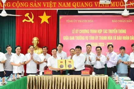 Phó Tổng Biên tập Báo Nhân Dân Quế Đình Nguyên và Phó Bí thư Thường trực Tỉnh ủy Thanh Hóa Lại Thế Nguyên trao nhau bản thỏa thuận hợp tác truyền thông giữa 2 cơ quan trước sự chứng kiến của lãnh đạo 2 đơn vị. (Ảnh: Thủy Nguyên)