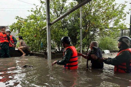 Lực lượng dân quân hỗ trợ người dân di dời khỏi khu vực bị ngập đến nơi an toàn.