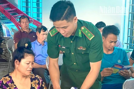 Cán bộ Đồn biên phòng Mường Lạn phát tờ gấp tuyên truyền pháp luật cho bà con dân tộc thiểu số tại xã biên giới Nậm Lạnh, huyện Sốp Cộp.