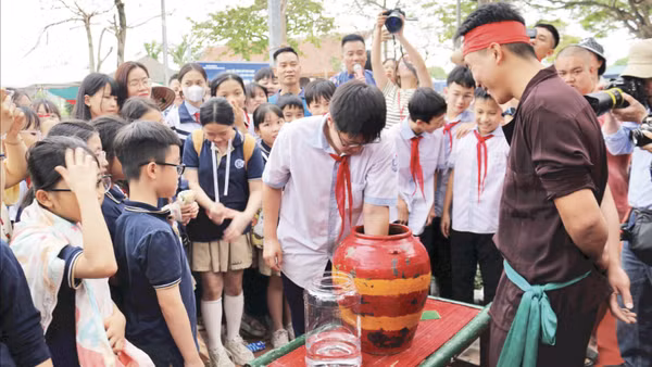 Học sinh thử tài bắt chạch trong chum tại phường rối Đào Thục, xã Thư Lâm, Hà Nội.