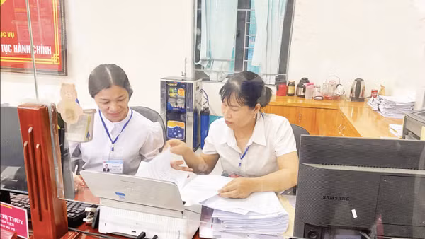 Đồng chí Phạm Thị Thúy (bên phải) cùng đồng nghiệp ở lại sau giờ làm việc tiếp tục nghiên cứu hồ sơ giúp nhân dân hoàn thành các thủ tục hành chính tại Trung tâm Phục vụ hành chính công.