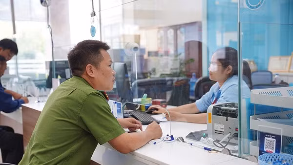 Thiếu tá Lò Văn Dũng làm thủ tục xác minh, chuyển hoàn số tiền cho người đã chuyển nhầm. Ảnh: ANH TUẤN