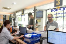 Nhân viên Bệnh viện Ung bướu Hà Nội hướng dẫn bệnh nhân làm các thủ tục khám, chữa bệnh bảo hiểm y tế. (Ảnh: KHÁNH AN)