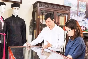 Liền anh Dương Đức Thắng giới thiệu các kỷ vật của người quan họ với du khách. 