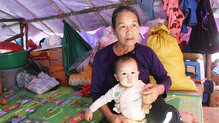 Bà Hứa Thị Bắc năm nay 65 tuổi cùng đứa cháu 10 tháng tuổi trong lán tạm dựng ven đồi tránh ngập. Ảnh: TÙNG VÂN 52.jpg