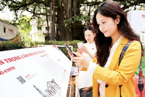 Các bạn trẻ quét mã QR xem thông tin các trận đánh tại triển lãm tương tác do Báo Nhân Dân tổ chức dịp kỷ niệm 50 năm Ngày Giải phóng miền nam, thống nhất đất nước. Ảnh | THẾ ĐẠI