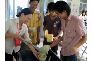 Chị Hồ Phương Thảo phát cháo cho bệnh nhân nghèo.