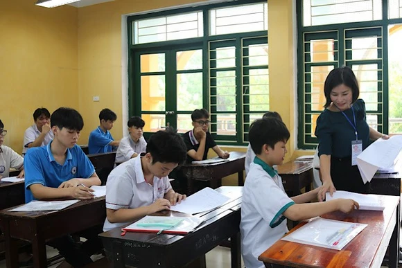 Giám thị phát giấy thi cho học sinh.