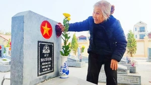 Một người vợ đang chăm sóc bia mộ của chồng. Ảnh: KHOA ĐÌNH