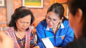 Đoàn viên, thanh niên phường Hoàn Kiếm (Hà Nội) hỗ trợ người dân thực hiện thủ tục hành chính công trên thiết bị điện thoại thông minh. Ảnh: PHẠM HẬU (TTXVN)
