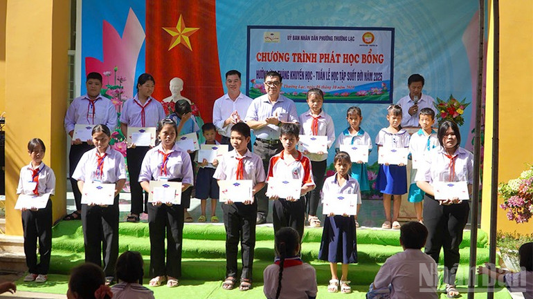 Đại diện Quỹ Xã hội Cỏ May và Báo Nhân Dân trao học bổng tặng học sinh. ndo_br_traohb9.jpg