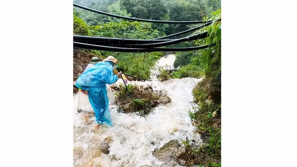 Nước tràn qua lối đi, người trekking dò bước qua đoạn đường dốc. Ảnh: VÂN TRANG