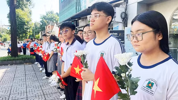 Các em học sinh cầm hoa cúc trắng tiễn biệt các Anh hùng liệt sĩ.
