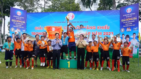 Anh Sanh (người nâng cúp) khoe cúp vô địch cùng các cầu thủ trẻ tại một giải đấu. Ảnh: NVCC