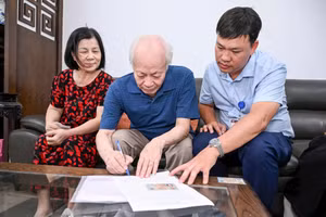 Anh Lê Minh Thiện (phải) hỗ trợ ông Nguyễn Xuân Bình làm thủ tục ủy quyền lương hưu. Ảnh: Thành Đạt 