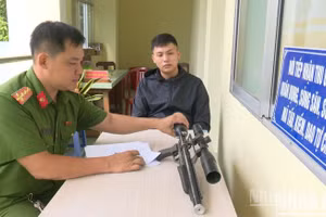 Anh Phạm Minh Sang giao nộp khẩu súng quân dụng nhặt được cho Công an xã Chợ Gạo. (Ảnh: LÊ HOÀI)