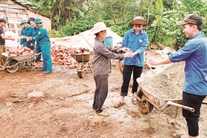 Anh Hoàng Văn Mạnh cùng mẹ là bà Hoàng Thị Đoàn mời nước, động viên lực lượng hỗ trợ xây dựng nhà mới cho gia đình.