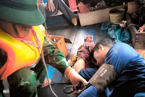 Nhân viên quân y Đồn Biên phòng Nhật Lệ sơ cứu cho nạn nhân ngay khi tàu cá cập bờ. (Ảnh: HƯƠNG GIANG)