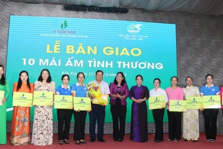 Đại diện Báo Nhân Dân trao bảng tượng trưng bàn giao 10 căn nhà mái ấm tình thương cho phụ nữ có hoàn cảnh khó khăn trên địa bàn. (Ảnh: HOÀNG TRUNG)