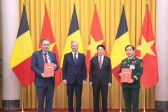 Trung tướng Nguyễn Hữu Chính (ngoài cùng bên phải) và Bộ trưởng, Thủ hiến vùng Brussels, Vương quốc Bỉ (ngoài cùng bên trái) trao đổi Thỏa thuận nguyên tắc về hỗ trợ nạn nhân chất độc da cam Việt Nam, với sự chứng kiến của Nhà vua Philippe (Vương quốc Bỉ) và Chủ tịch nước Lương Cường.