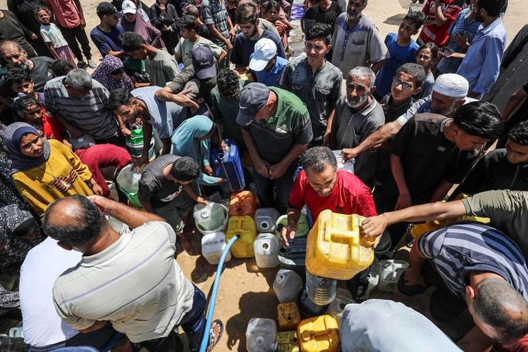 Người dân Gaza nhận nước tại một khu vực di tản. (Ảnh: Tân Hoa xã) nguoi-dan-nhan-nuoc-tai-leu-trai-tam-thoi-ngay-16626.jpg