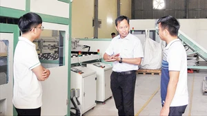 Tiến sĩ Đỗ Thế Cần (giữa) cùng cộng sự bên cạnh dây chuyền xử lý pin mặt trời.