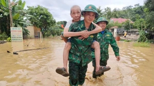 Bộ đội Biên phòng Tam Quang cõng đưa một cụ ông đến nơi an toàn. (Ảnh: HẢI THƯỢNG)