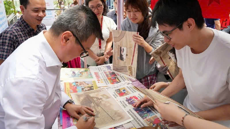 Tổng Biên tập Báo Nhân Dân trực tiếp phát báo và ký tặng bạn đọc tại không gian Triển lãm.