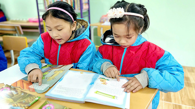 Các em học sinh đọc sách tại thư viện của Trường Phổ thông dân tộc bán trú Tiểu học Ngam La. (Ảnh NFVC)
